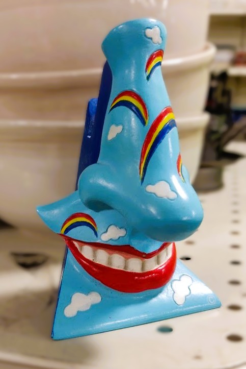 A statue of a smiling mouth and nose, blue and raindbow colored.