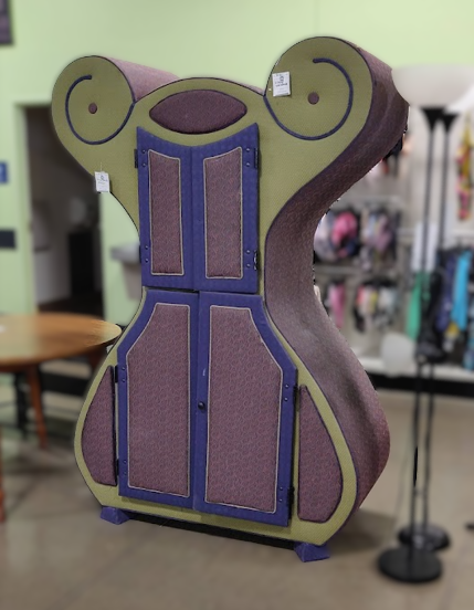 A large hourglass-shaped upholstered wardrobe, colored puek green and purple.